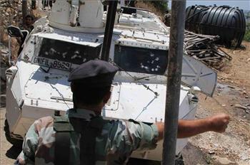 جندي لبناني وأمامه آلية دولية بدت عليها آثار رشق الحجارة