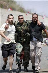 مواطنان يساعدون جندياً جريحاً في العديسة (رويترز)