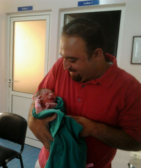 علي كامل أبو عبّاس حاملاً مولوده الجديد كمل