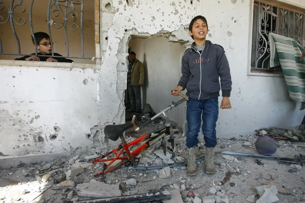 لطفل حسن يحمل دراجته التي اصابها القصف وبدت الفجوة في المنزل