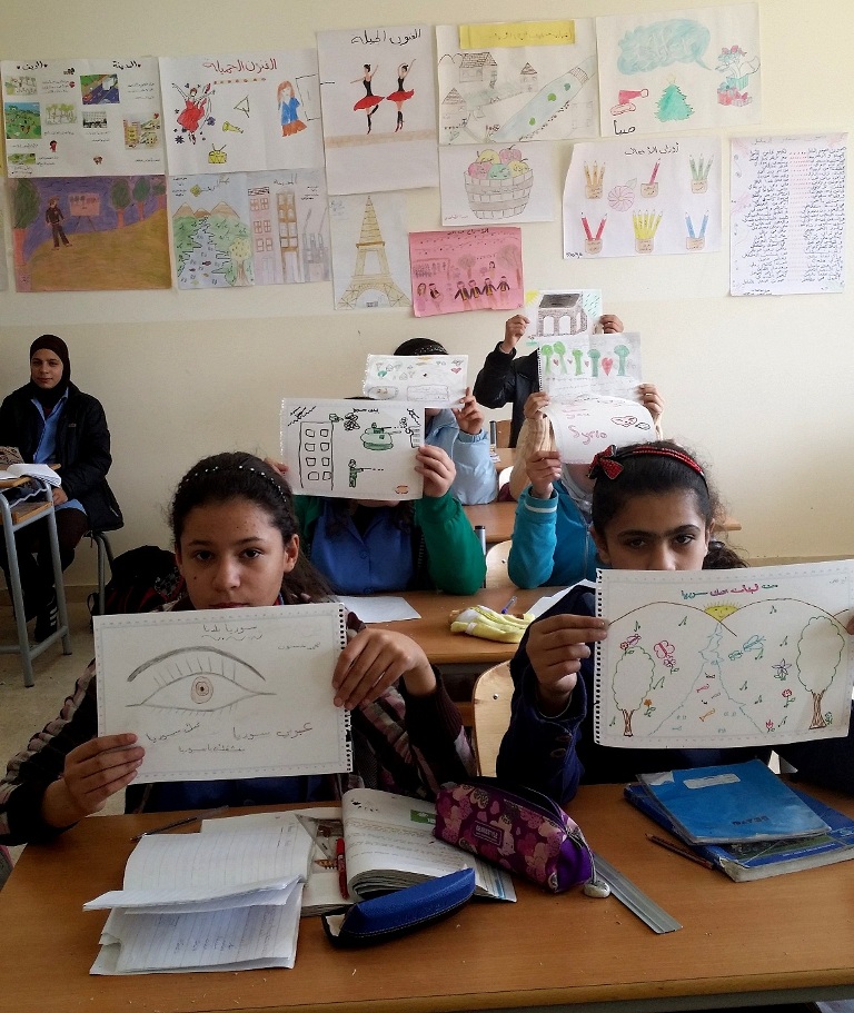 طلاب سوريون يرفعون رسوماتهم بعد إنجازها في أحد مدارس تجمعات السوريين في لبنان