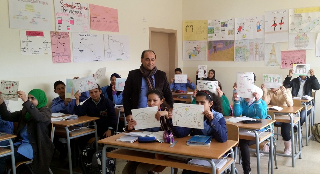 الطلاب السوريون يرفعون رسوماتهم المنجزة في أحد المدارس شمال لبنان ومعهم رئيس الجمعية شوقي دلال