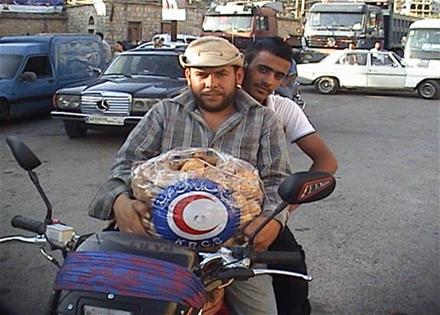نازح سوري ينقل حصته على دراجته النارية