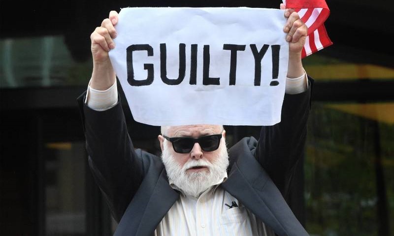 متظاهر يرفع لافتة كتب عليها مذنب امام المحكمة التي يمثل فيها بول مانافورت مدير الحملة الانتخابية لترامب السابق في فيرجينيا (أ ف ب).