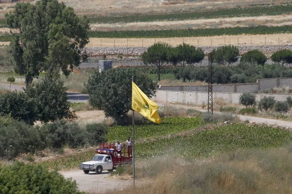 سيارة بيك أب لبنانية تمرّ بالقرب من علم حزب الله عبر الحدود بالقرب من قرية عيترون (أ ف ب)