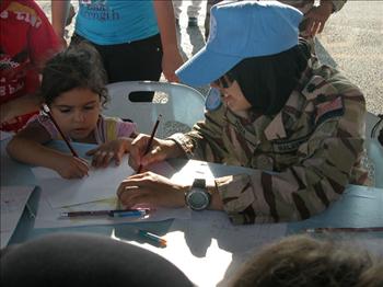 ضابطة من اليونيفيل تساعد تلميذة روضة على تعلم الكتابة