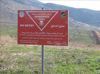 لافتة تحذر المواطنين من الالغام عند مدخل الحقل