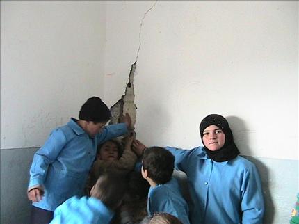 تلامذة مدرسة حلتا يشيرون إلى تصدعات جدار في غرفة الصف