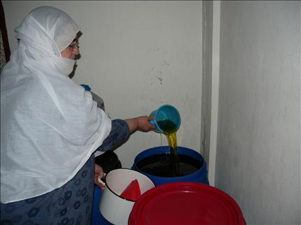 مزارعة تفحص زيتها المكدس في الخوابي (طارق أبو حمدان)