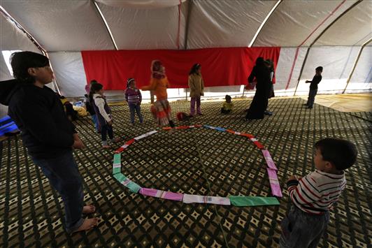 اطفال نازحون داخل خيمة في ريف ادلب امس (رويترز)