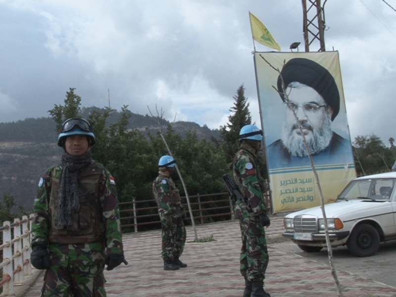 عناصر من الوحدة الاندونيسية تراقب الخط الازرق وبدت صورة للامين العام لحزب الله