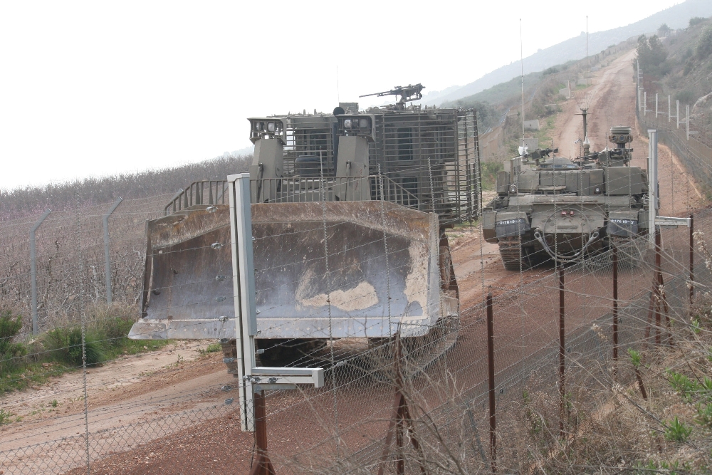 جرافة للعدو تسير بمحاذاة السياج التقني تؤازرها مجنزرة