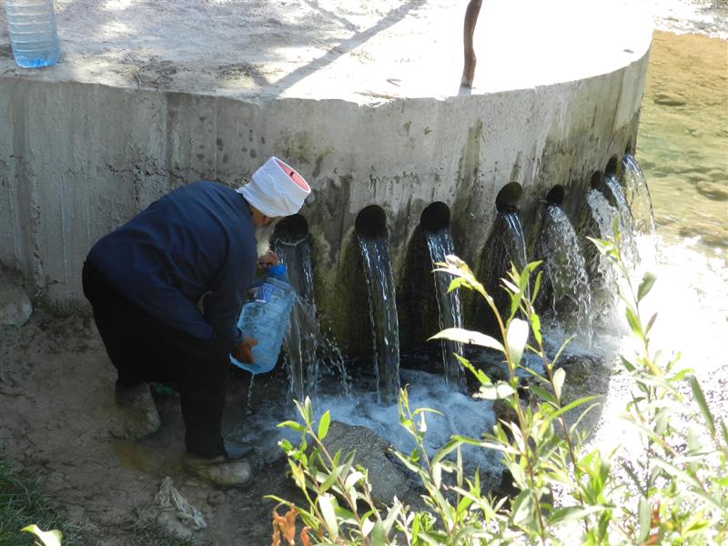 يملأ غالون مياه من نبع الحاصباني (طارق أبو حمدان)