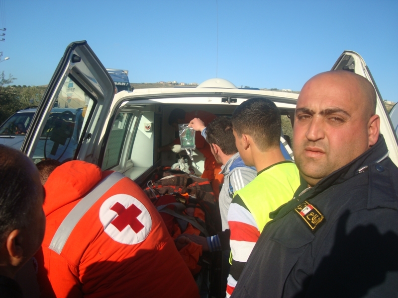 عناصر الصليب الاحمر والدفاع المدني يخرجون الجريح من السيارة لنقله بسيارة الاسعاف