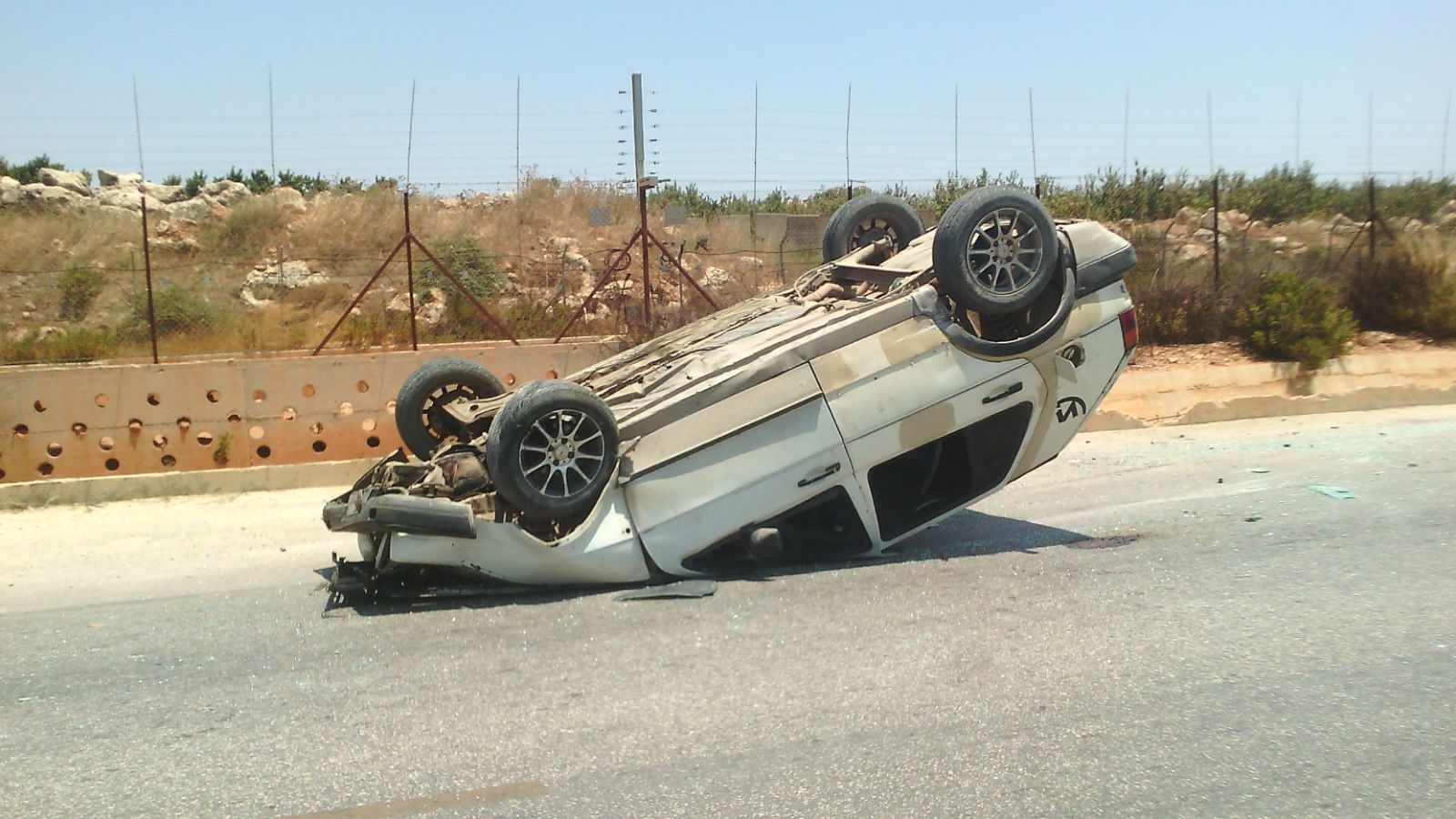 السيارة التي انقلبت على سطحها عند الحدود الفاصلة مما أدى إلى إصابة شقيقين بجروح جراء الحادث
