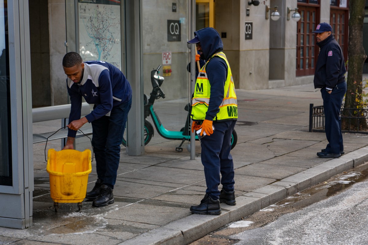عمال ينظفون بقع الدماء في موقع إطلاق النار على عنصرين من الحرس الوطني في واشنطن. (أف ب).