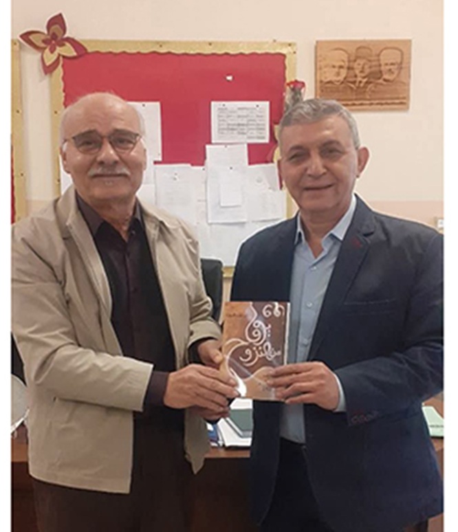 ابراهيم مصطفى يتسلم الكتاب من الصحافي الزميل علي بدرالدين