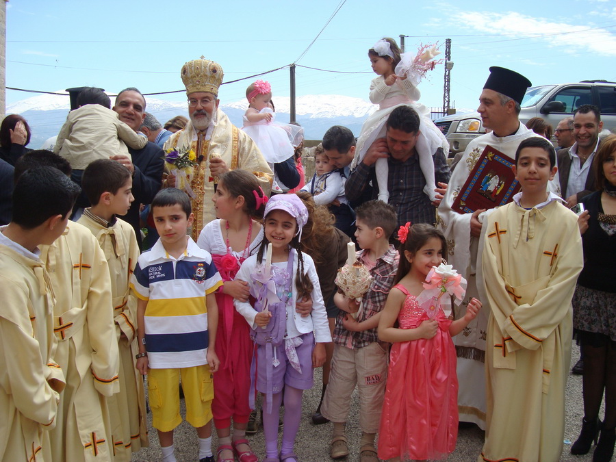 المطران حداد يحيط به الاطفال خلال زياح احد الشعانين في كنيسة مار بطرس في مرجعيون (أرشيف)